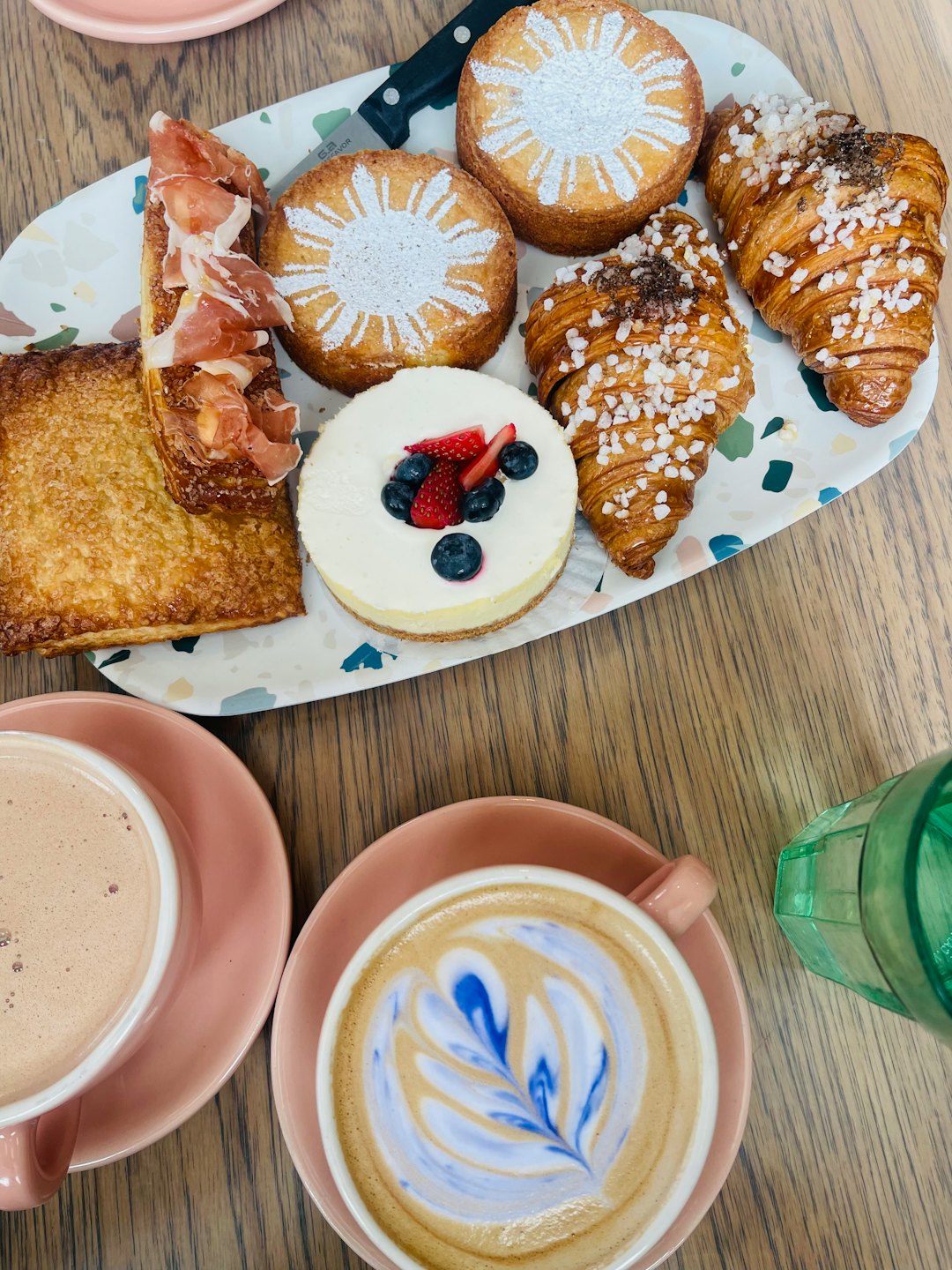 Colorful pastries on a white tray with hot drinks on a wooden table.