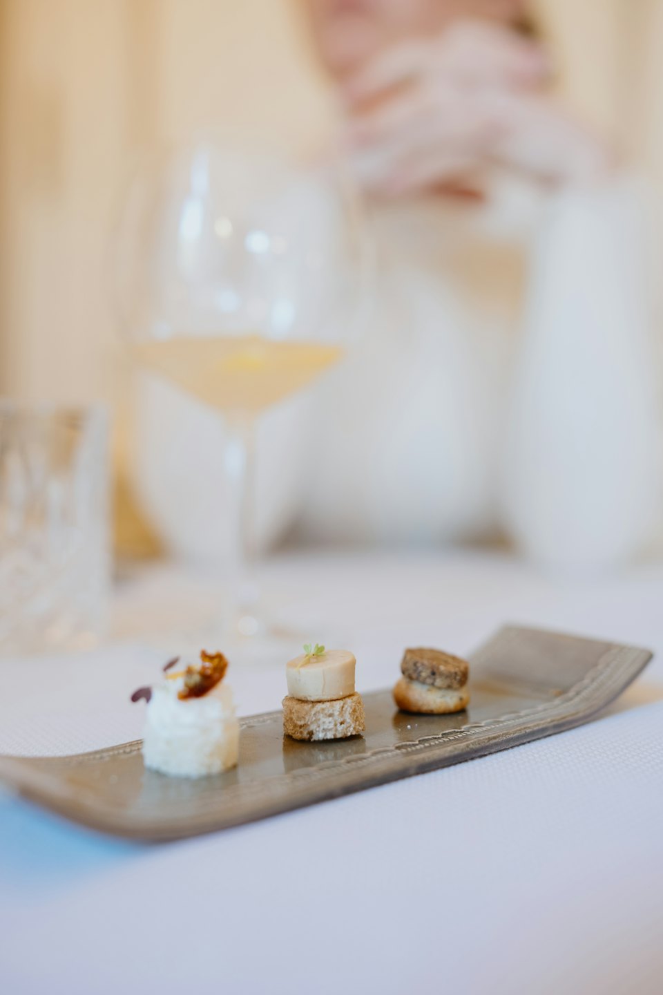 Three gourmet appetizers artfully arranged on a grey serving tray.