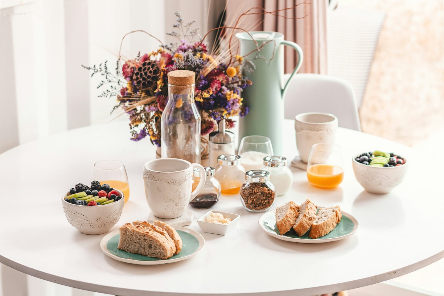 A breakfast spread with fruit, bread, and drinks on a table.