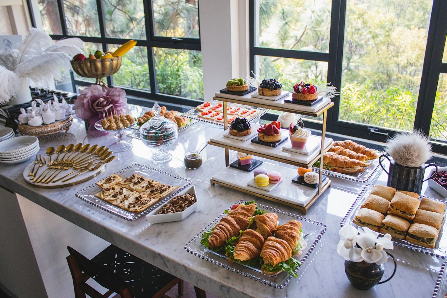 Lavish buffet table with sweet and savory dishes and ostrich feathers.