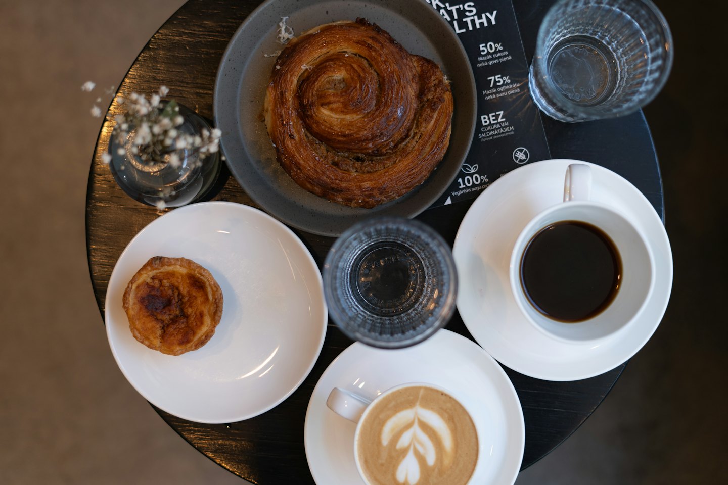 Two coffees and two pastries sit on a wooden table.