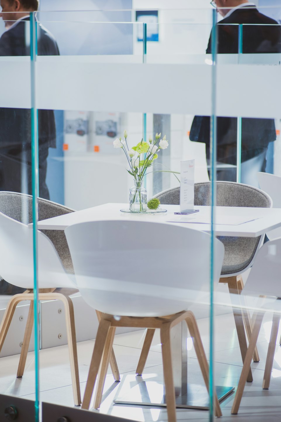 Modern office break area with glass partitions and floral decor.