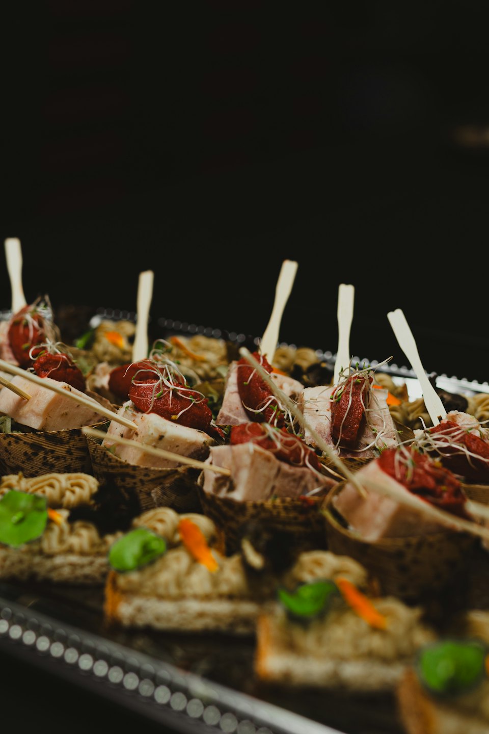 Gourmet appetizers arranged on a silver catering tray.