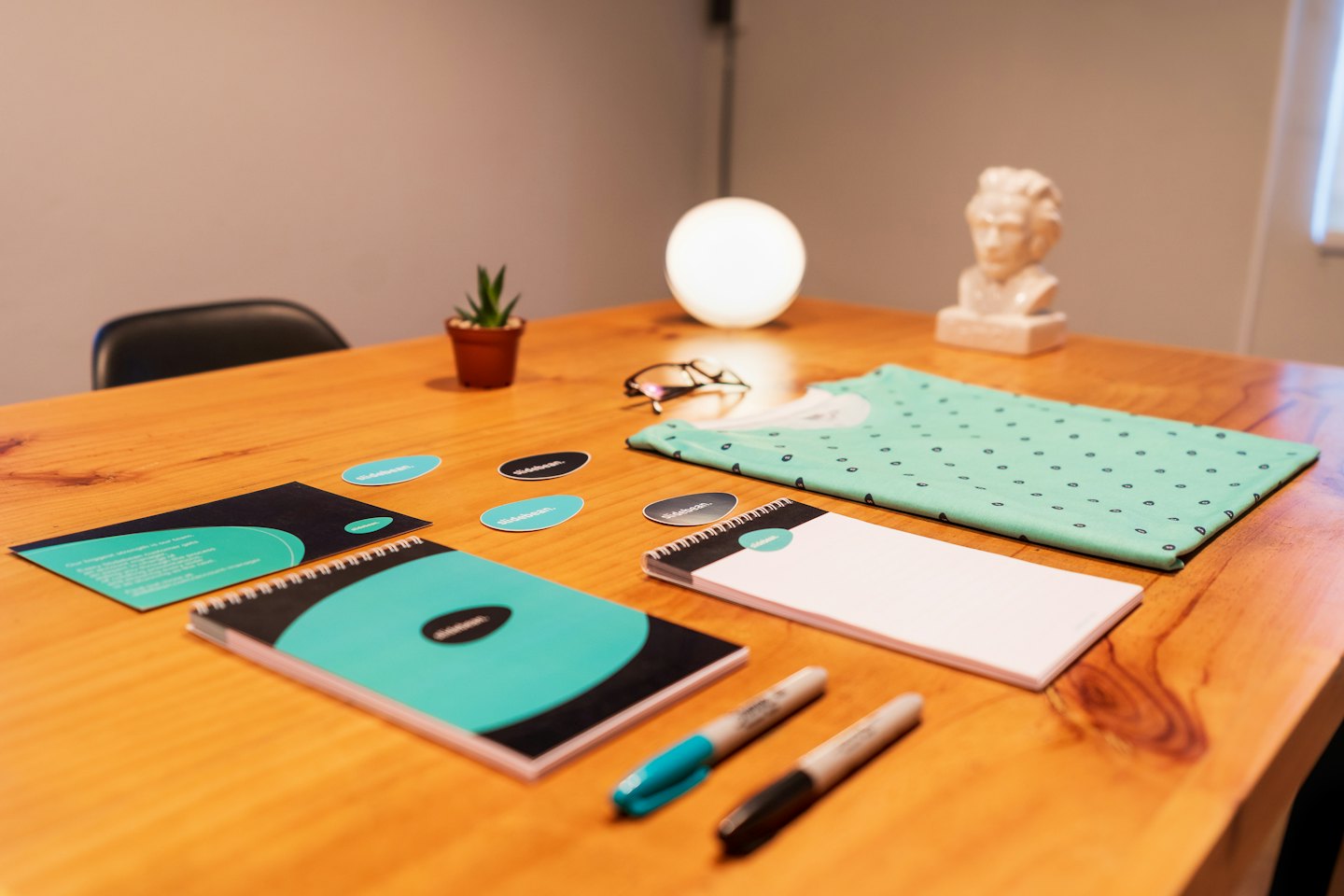 Corporate merchandise and office supplies on a wooden conference table.